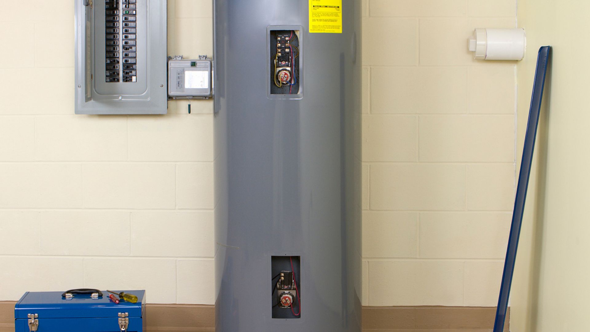 Large gray water heater with electrical panel and blue toolbox