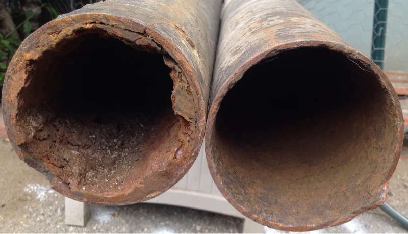 Two rusty, corroded metal pipes with rough interior surfaces
